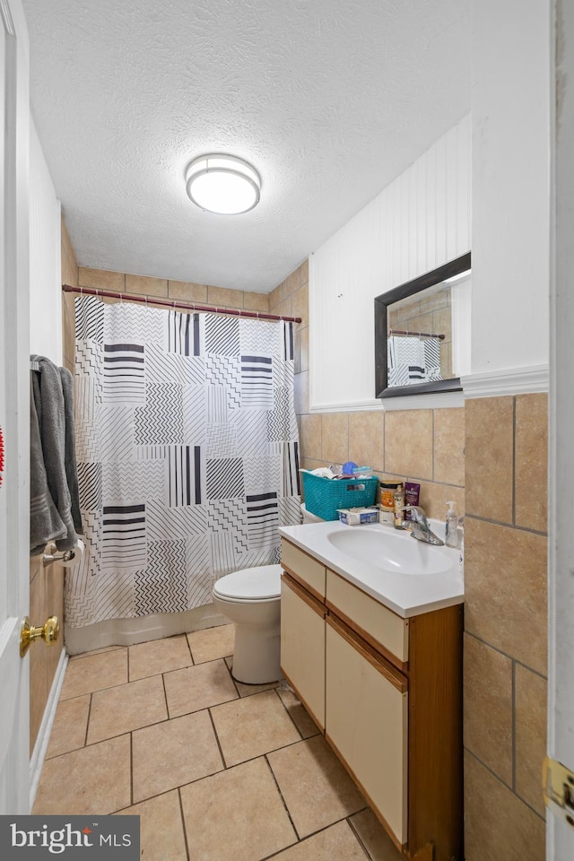 bathroom with vanity, a textured ceiling, tile walls, tile patterned flooring, and toilet