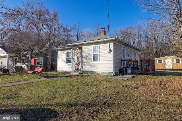 view of front facade with a wooden deck, a front lawn, and a storage shed