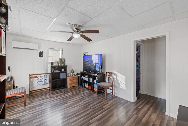 sitting room featuring a wall mounted air conditioner, a paneled ceiling, dark hardwood / wood-style floors, and ceiling fan