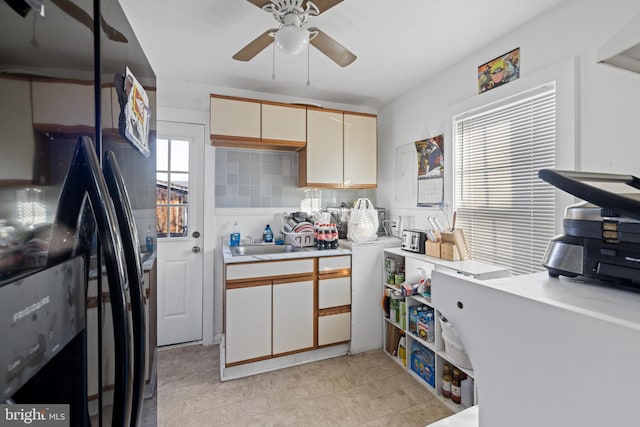 kitchen featuring white cabinets, decorative backsplash, black fridge, and ceiling fan