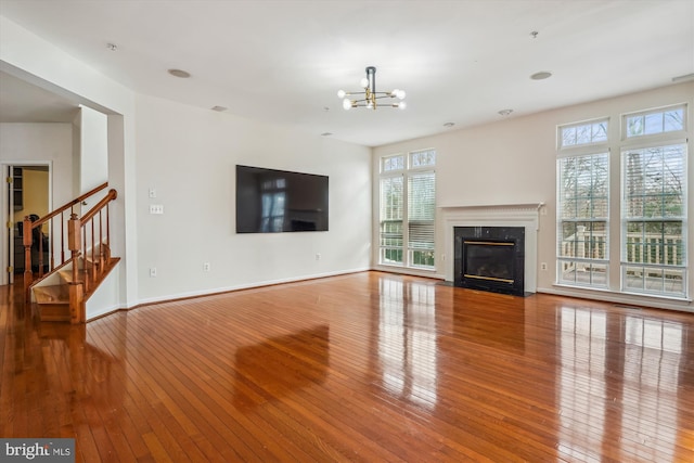 unfurnished living room with a high end fireplace, light wood-type flooring, and an inviting chandelier