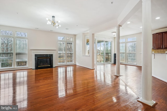 unfurnished living room featuring hardwood / wood-style floors, a wealth of natural light, and a notable chandelier