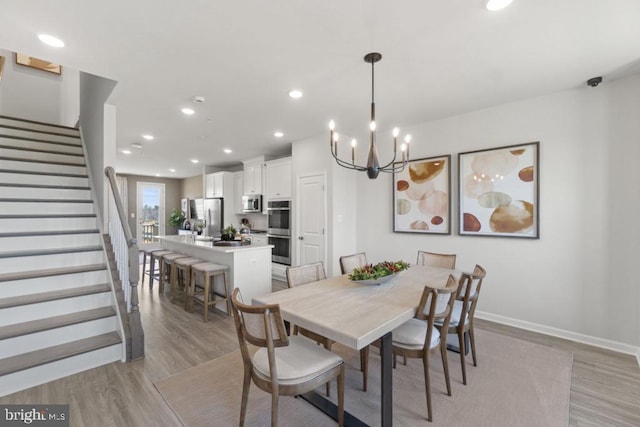 dining space with an inviting chandelier and light hardwood / wood-style flooring