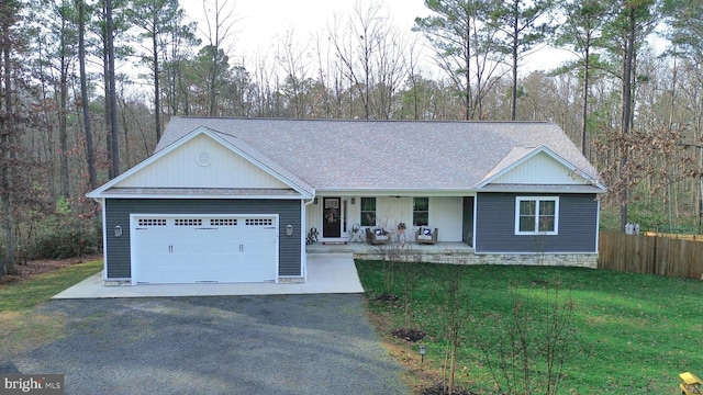 view of front of home featuring covered porch, a garage, and a front yard