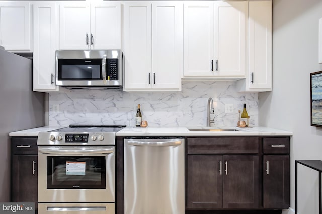 kitchen featuring decorative backsplash, dark brown cabinetry, stainless steel appliances, sink, and white cabinetry