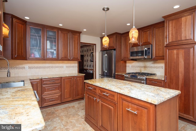 kitchen featuring sink, light stone counters, pendant lighting, decorative backsplash, and appliances with stainless steel finishes