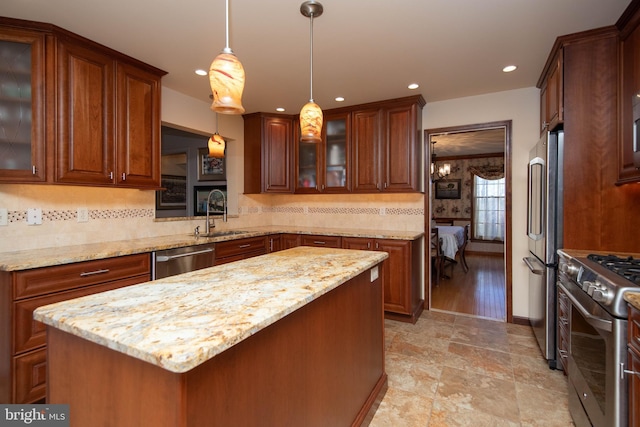 kitchen with appliances with stainless steel finishes, backsplash, sink, a center island, and hanging light fixtures