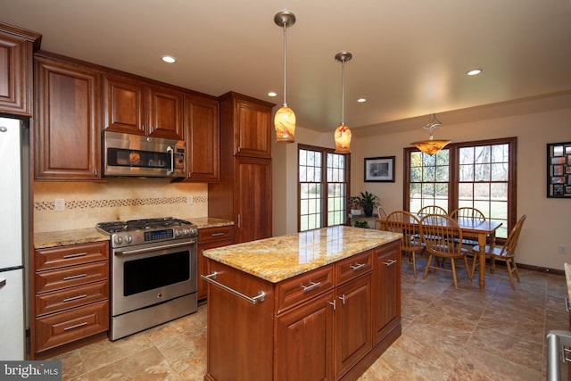 kitchen featuring light stone countertops, stainless steel appliances, backsplash, decorative light fixtures, and a kitchen island