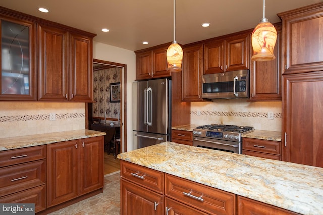 kitchen featuring pendant lighting, light stone countertops, and appliances with stainless steel finishes