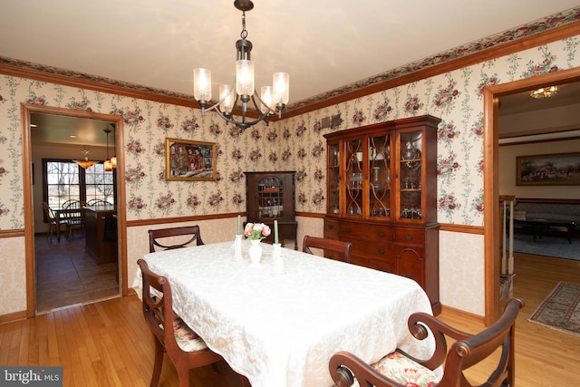 dining room with ornamental molding, light hardwood / wood-style floors, and a notable chandelier