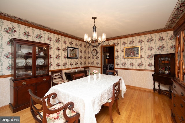 dining room with light hardwood / wood-style flooring, ornamental molding, and an inviting chandelier