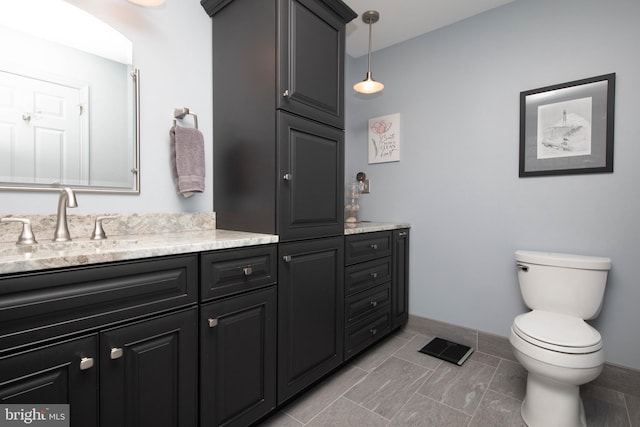 bathroom with toilet, vanity, and tile patterned floors