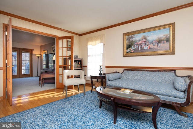 living area with hardwood / wood-style flooring, a healthy amount of sunlight, crown molding, and french doors