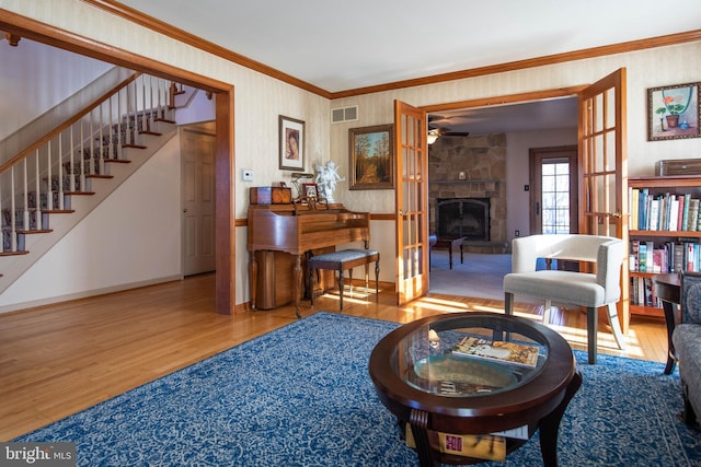 living room with hardwood / wood-style floors, french doors, ceiling fan, ornamental molding, and a fireplace