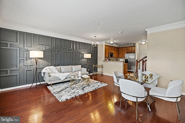 living room featuring dark wood-type flooring, crown molding, and a notable chandelier