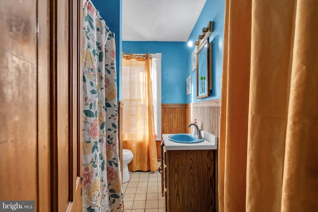 bathroom with curtained shower, tile patterned floors, a textured ceiling, toilet, and vanity