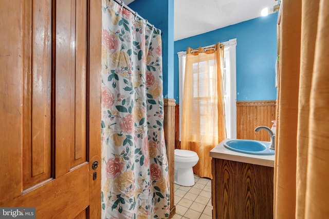 bathroom featuring vanity, wooden walls, tile patterned flooring, a shower with shower curtain, and toilet