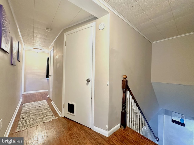 corridor with hardwood / wood-style floors and ornamental molding