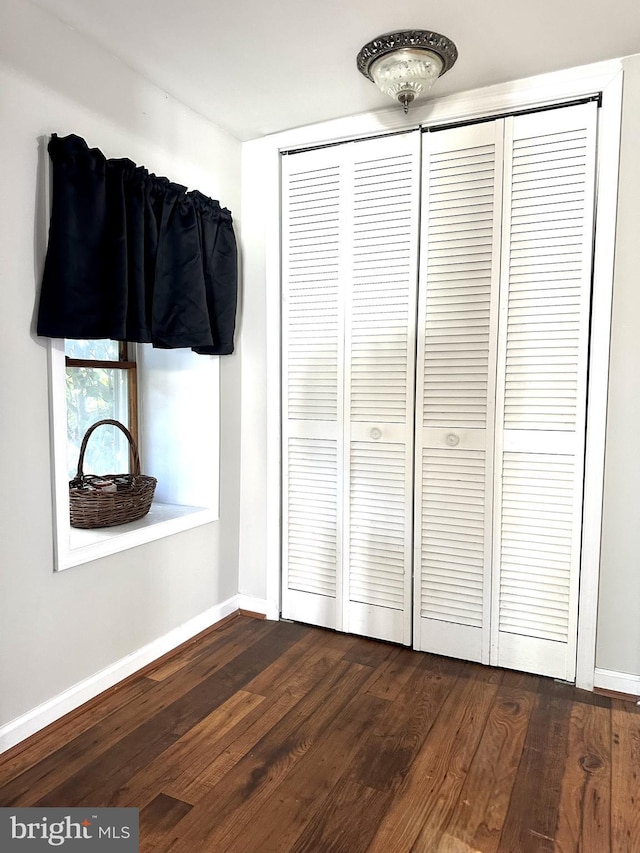 unfurnished bedroom featuring dark hardwood / wood-style flooring and a closet