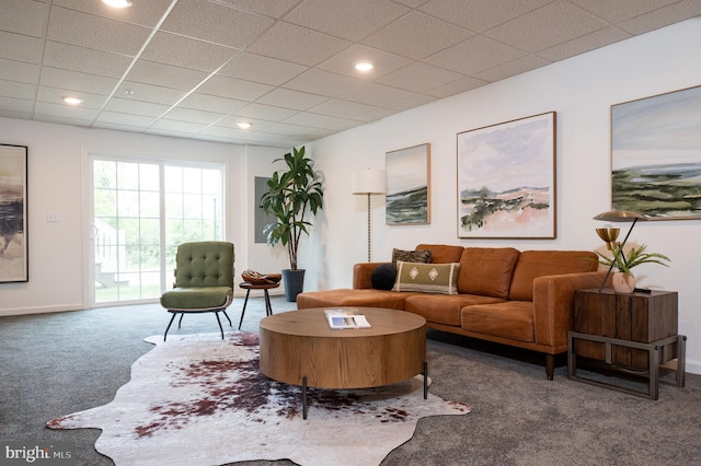 living room featuring dark carpet and a drop ceiling