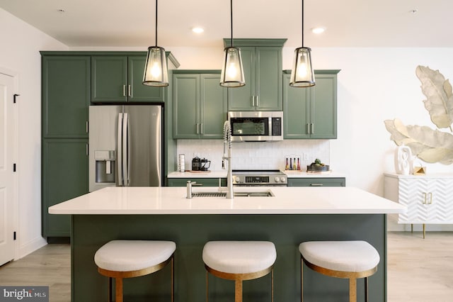 kitchen with a center island with sink, stainless steel appliances, and light wood-type flooring