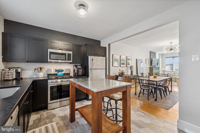 kitchen featuring sink, light hardwood / wood-style flooring, decorative backsplash, a notable chandelier, and stainless steel appliances