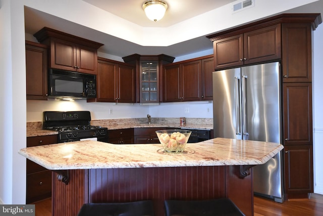 kitchen featuring dark hardwood / wood-style flooring, a center island, a breakfast bar area, and black appliances