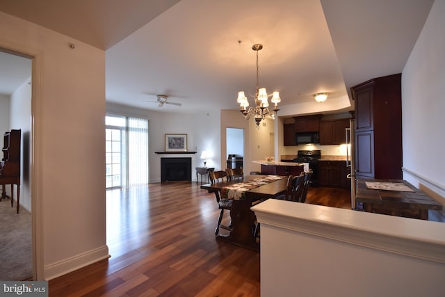 kitchen with pendant lighting, black appliances, ceiling fan with notable chandelier, dark hardwood / wood-style flooring, and dark brown cabinetry