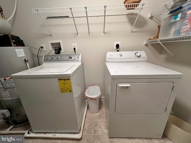 laundry room with light tile patterned flooring, washing machine and dryer, and water heater