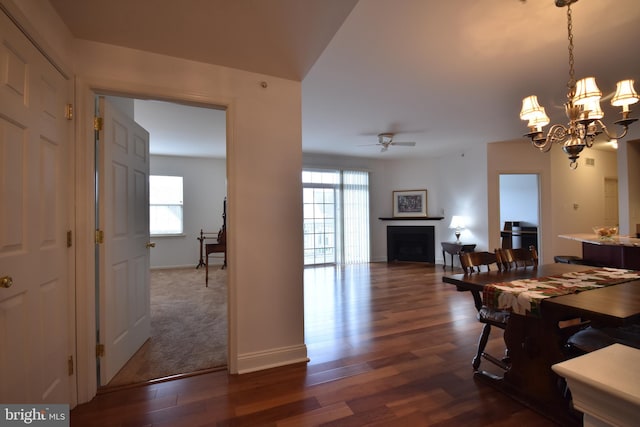 dining space featuring ceiling fan with notable chandelier, dark wood-type flooring, and a healthy amount of sunlight