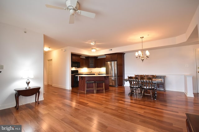 kitchen featuring dark brown cabinetry, a center island, dark hardwood / wood-style floors, black appliances, and ceiling fan with notable chandelier