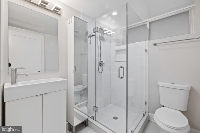 bathroom with an enclosed shower, vanity, and toilet