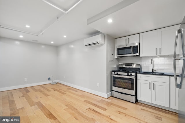 kitchen with a wall mounted air conditioner, sink, appliances with stainless steel finishes, tasteful backsplash, and white cabinetry