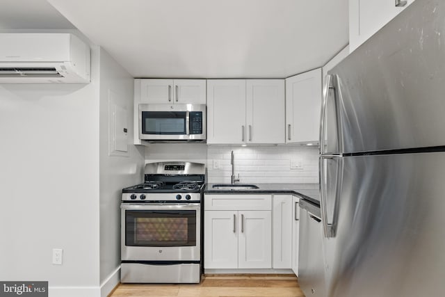 kitchen featuring white cabinets, sink, appliances with stainless steel finishes, light hardwood / wood-style floors, and a wall unit AC