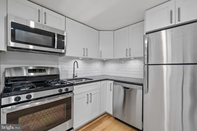 kitchen featuring white cabinets, sink, stainless steel appliances, and light hardwood / wood-style flooring