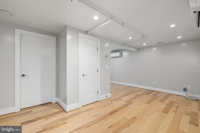 basement featuring light hardwood / wood-style flooring and an AC wall unit