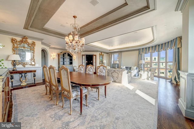 dining room with dark hardwood / wood-style flooring, a tray ceiling, crown molding, and a notable chandelier