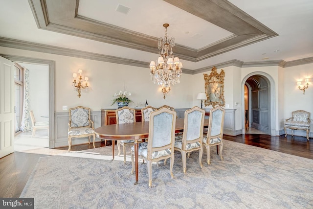 dining space with hardwood / wood-style floors, a chandelier, crown molding, and a tray ceiling