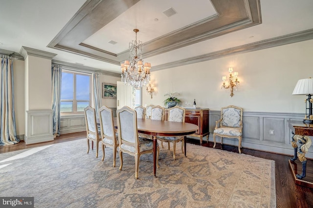 dining space with a notable chandelier, ornamental molding, dark wood-type flooring, and a tray ceiling