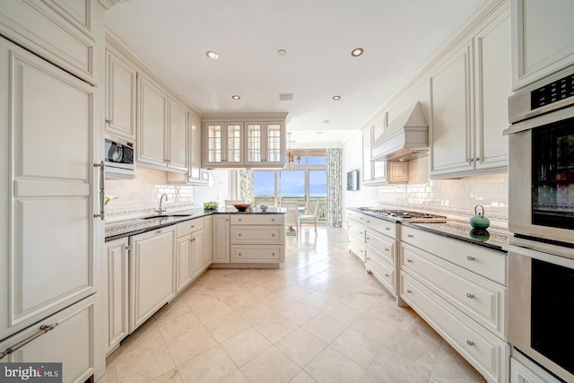 kitchen featuring custom exhaust hood, sink, decorative backsplash, appliances with stainless steel finishes, and kitchen peninsula