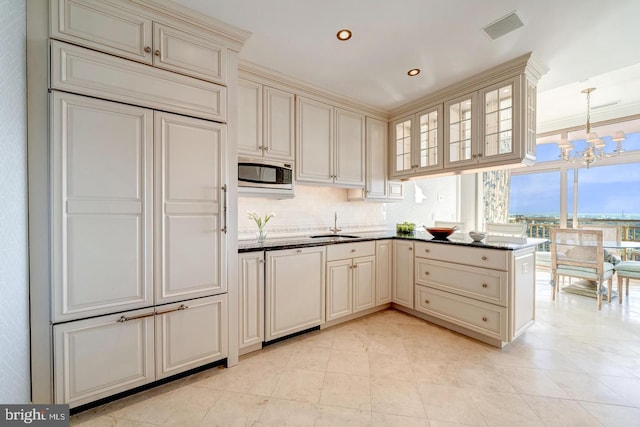 kitchen featuring tasteful backsplash, stainless steel microwave, white dishwasher, and cream cabinetry