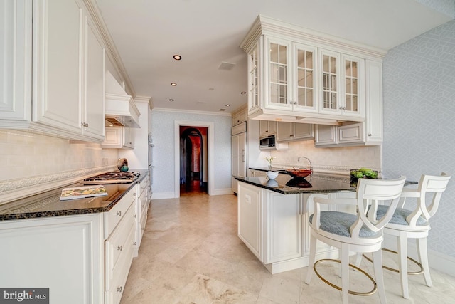 kitchen featuring a kitchen bar, white cabinets, premium range hood, and ornamental molding