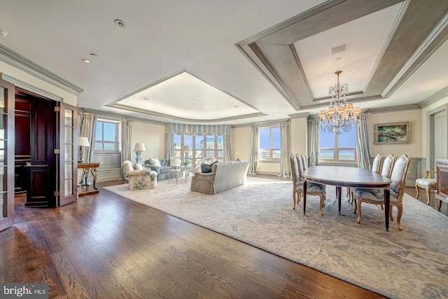 dining area featuring dark hardwood / wood-style flooring, a raised ceiling, crown molding, and a wealth of natural light