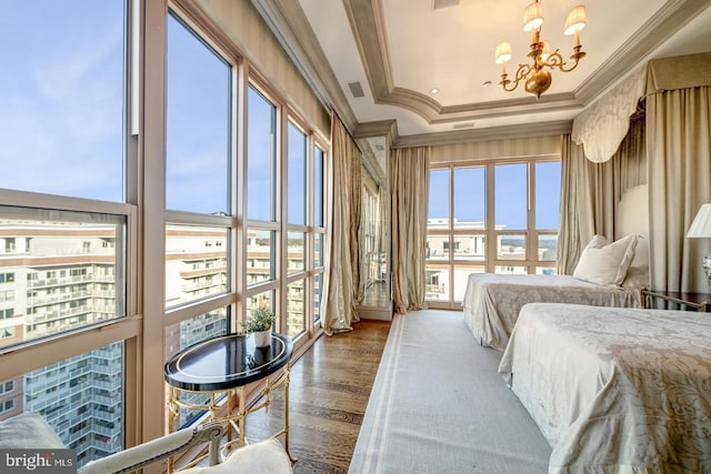 bedroom with a raised ceiling, crown molding, an inviting chandelier, and hardwood / wood-style flooring