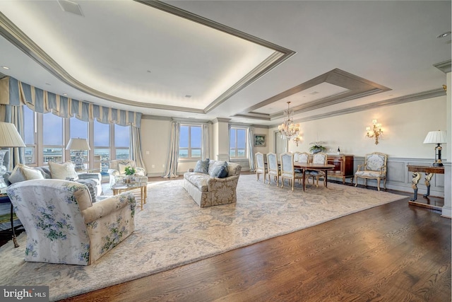 living room featuring hardwood / wood-style flooring, a chandelier, ornamental molding, and a tray ceiling