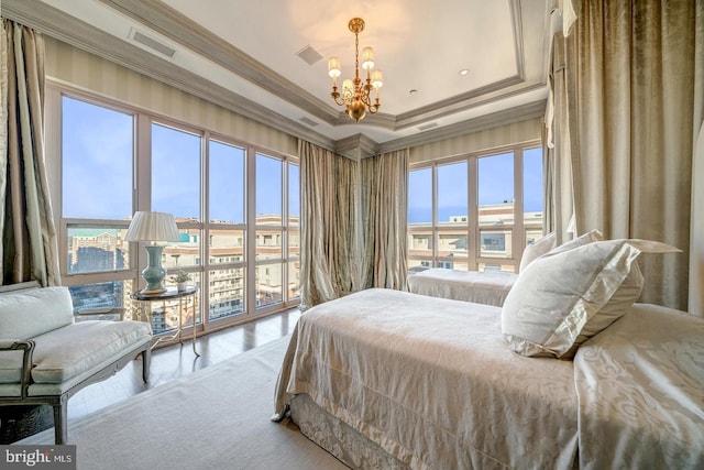 bedroom featuring a tray ceiling, multiple windows, crown molding, and hardwood / wood-style flooring