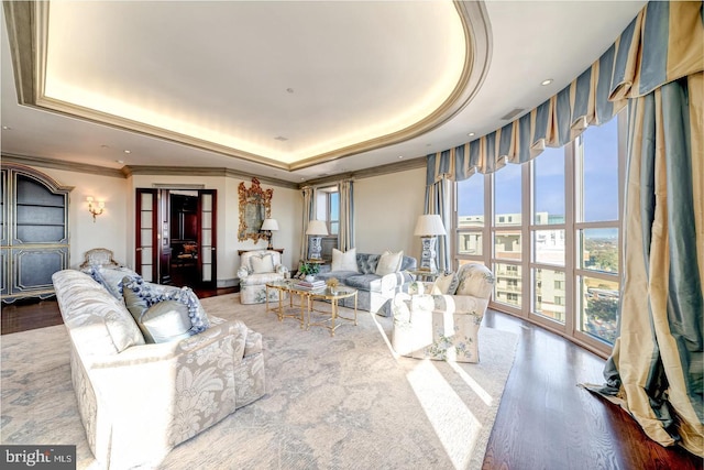 living room with a raised ceiling, ornamental molding, and hardwood / wood-style flooring