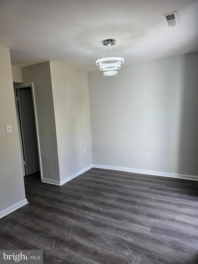 empty room with an inviting chandelier and dark hardwood / wood-style floors