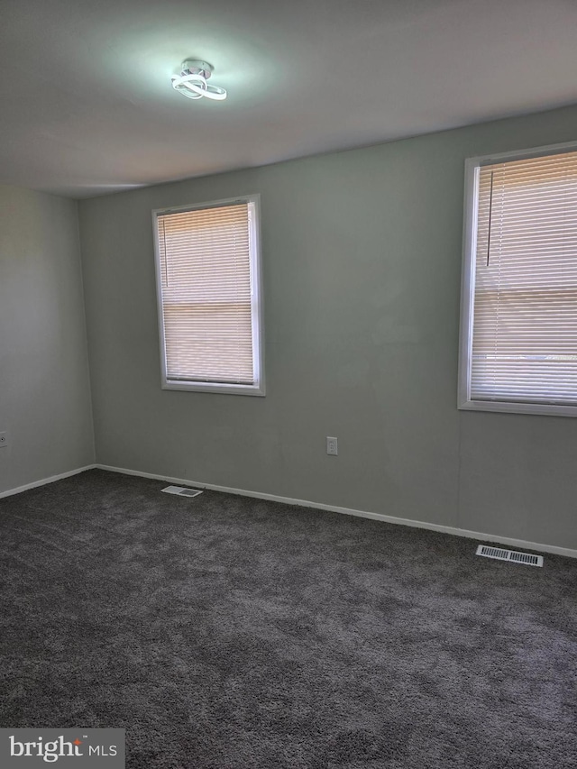 unfurnished room featuring dark carpet