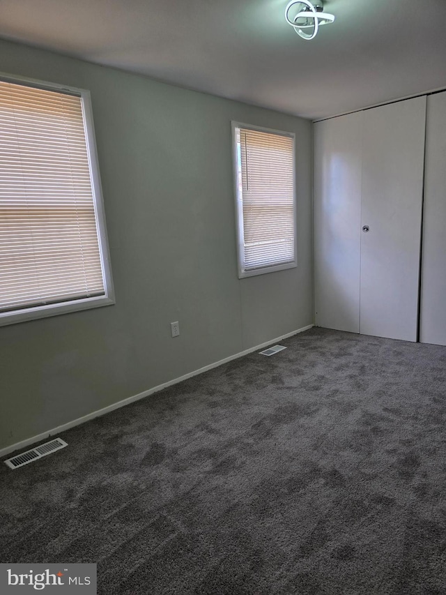 unfurnished bedroom with dark colored carpet and a closet